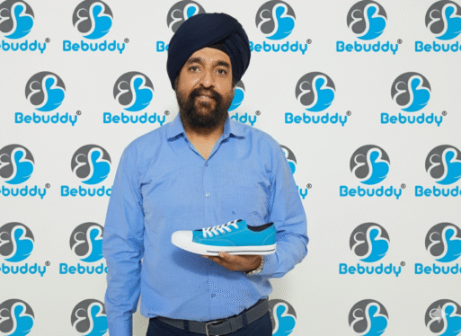 Brand owner holding a blue canvas shoe in front of a Bebuddy brand backdrop